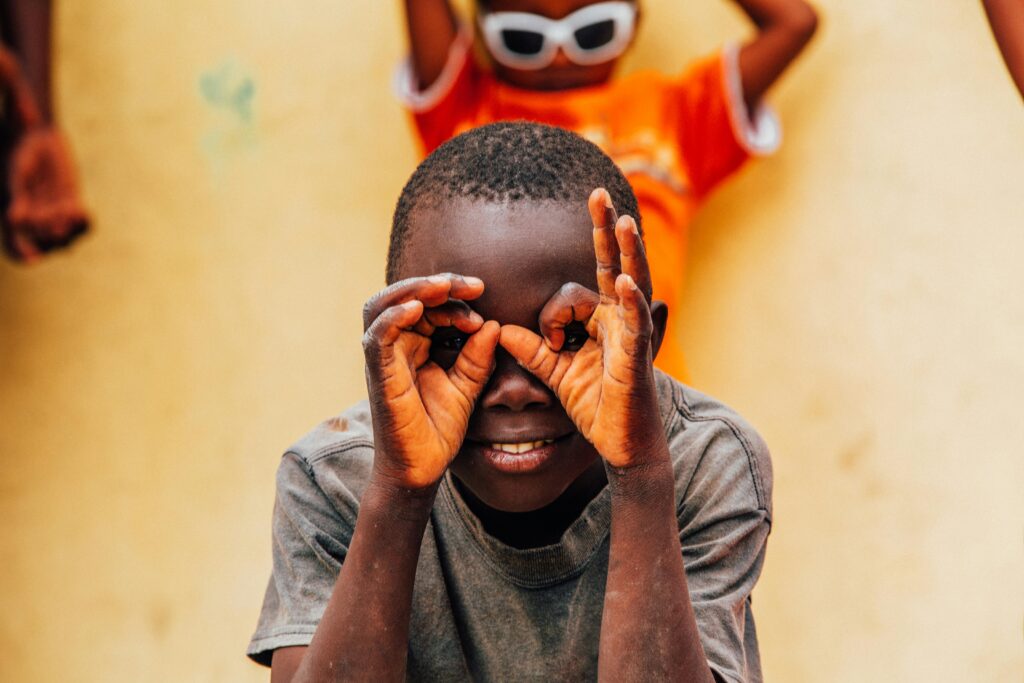 A smiling child playfully making hand gestures, creating a joyful moment.